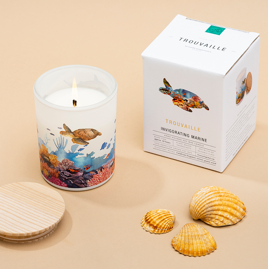 Candle with ocean-themed design and packaging on a beige background