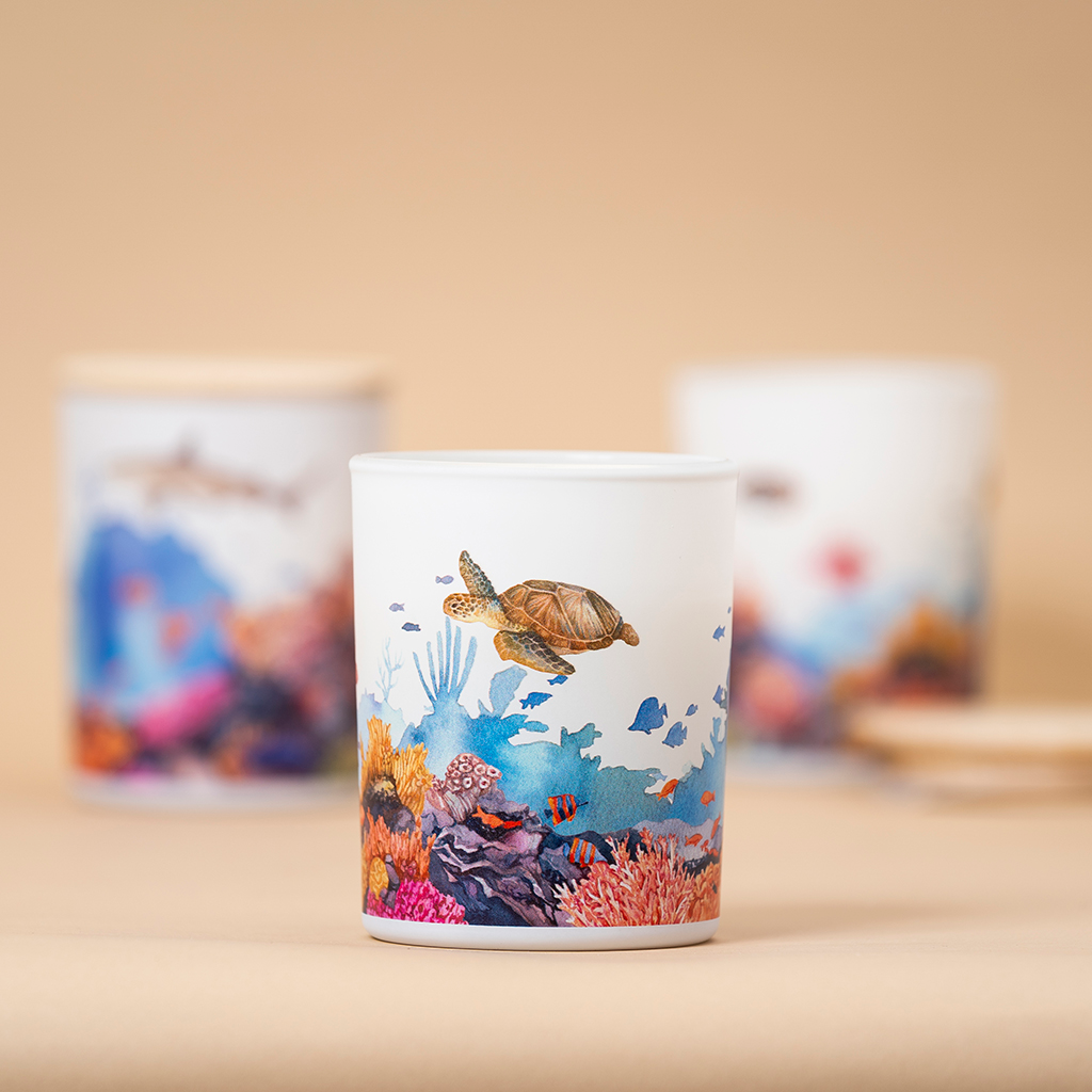 Ceramic candle holder with a turtle and coral design on a beige background