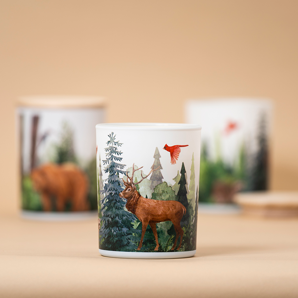 Ceramic candle holder with nature-themed design featuring a deer and trees on a beige background