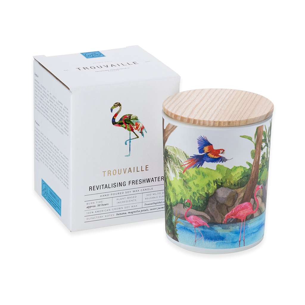 Candle with a colorful design of a parrot flying and two pink flamingos. The candle has a wooden lid next to its packaging box on a white background