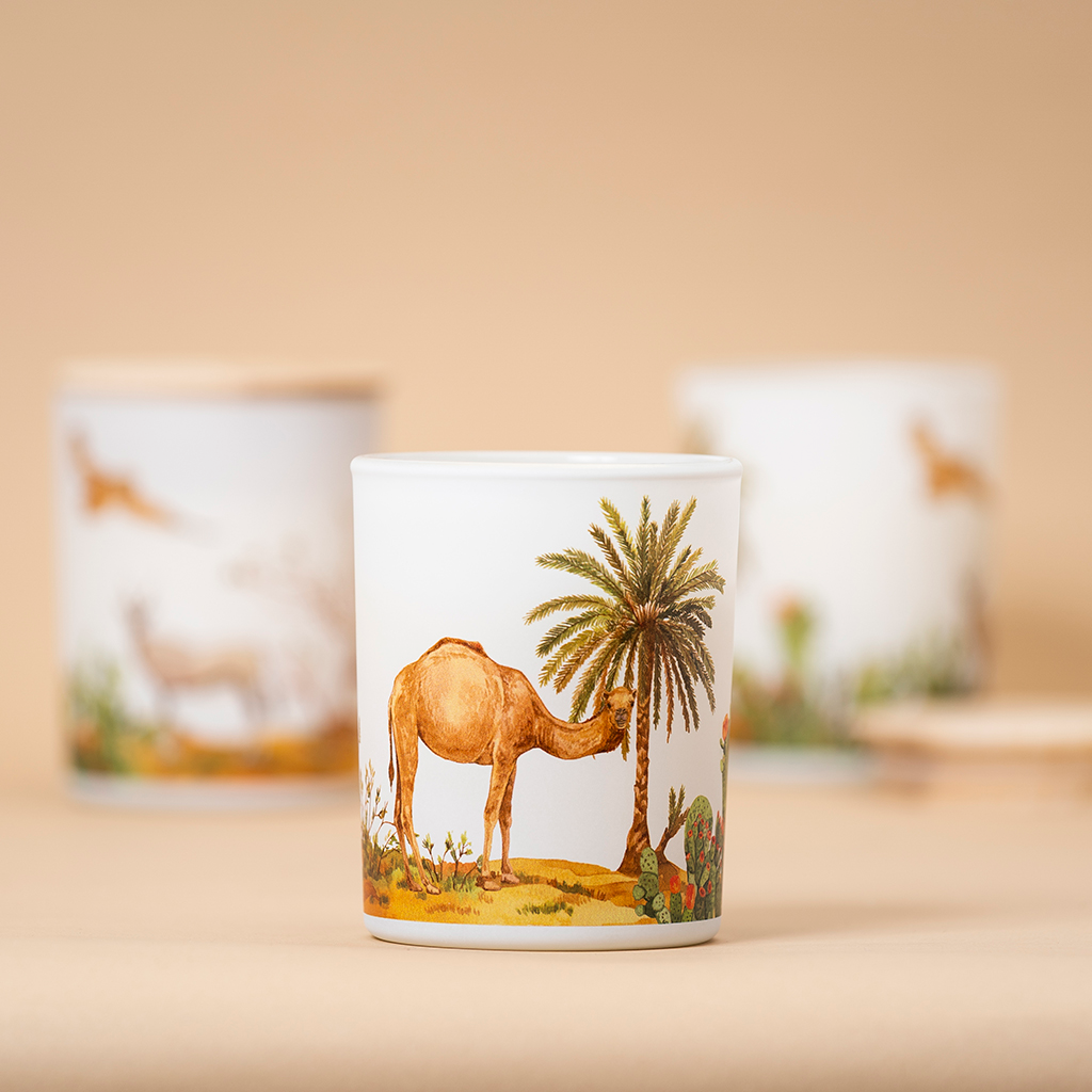 Ceramic candle holder with a desert scene featuring a camel and palm tree on a beige background.