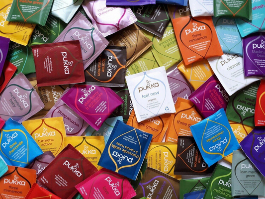 Assorted Pukka tea packets in various colors and designs.