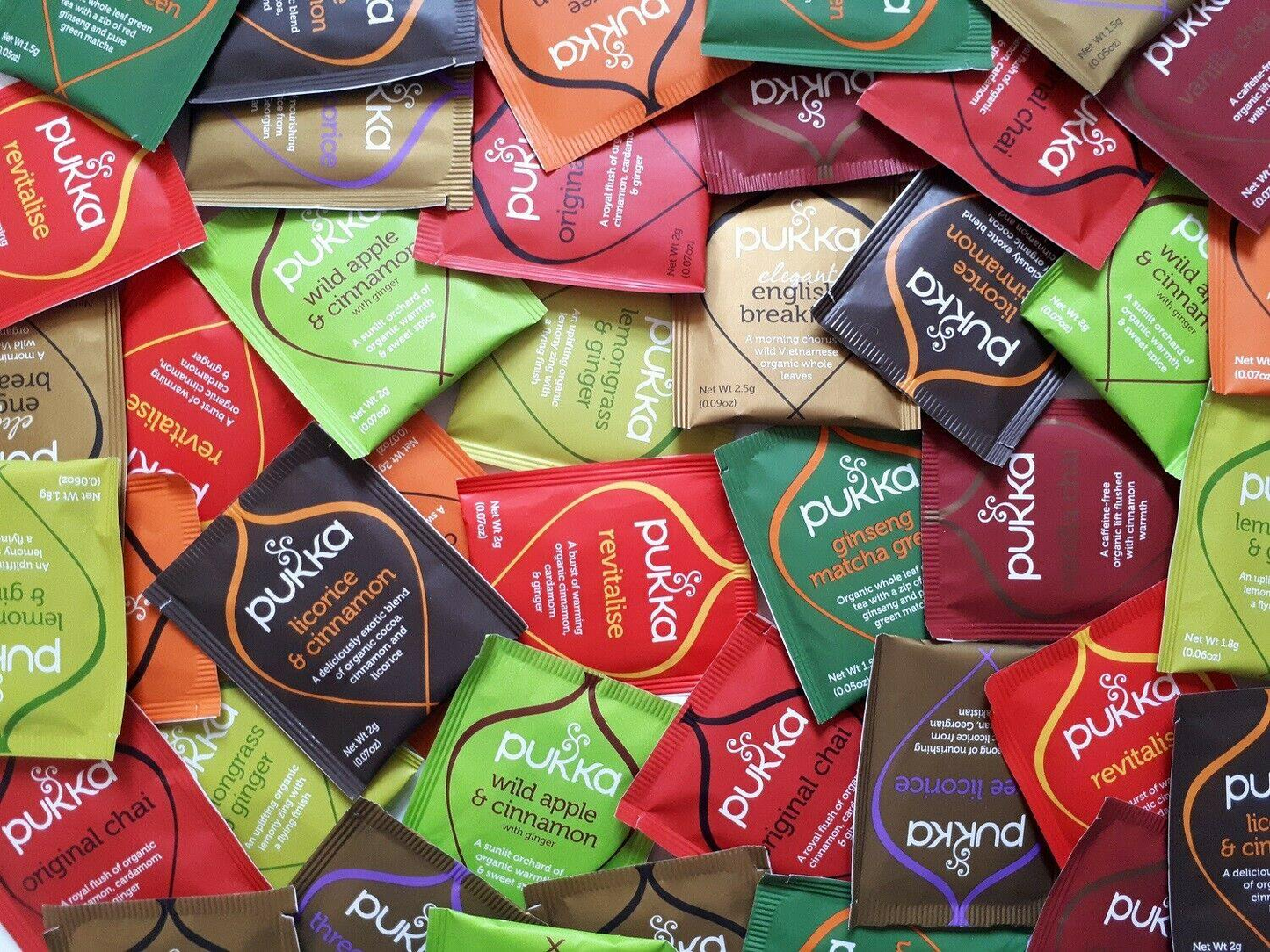 Assorted Pukka tea packets in various colors and designs.