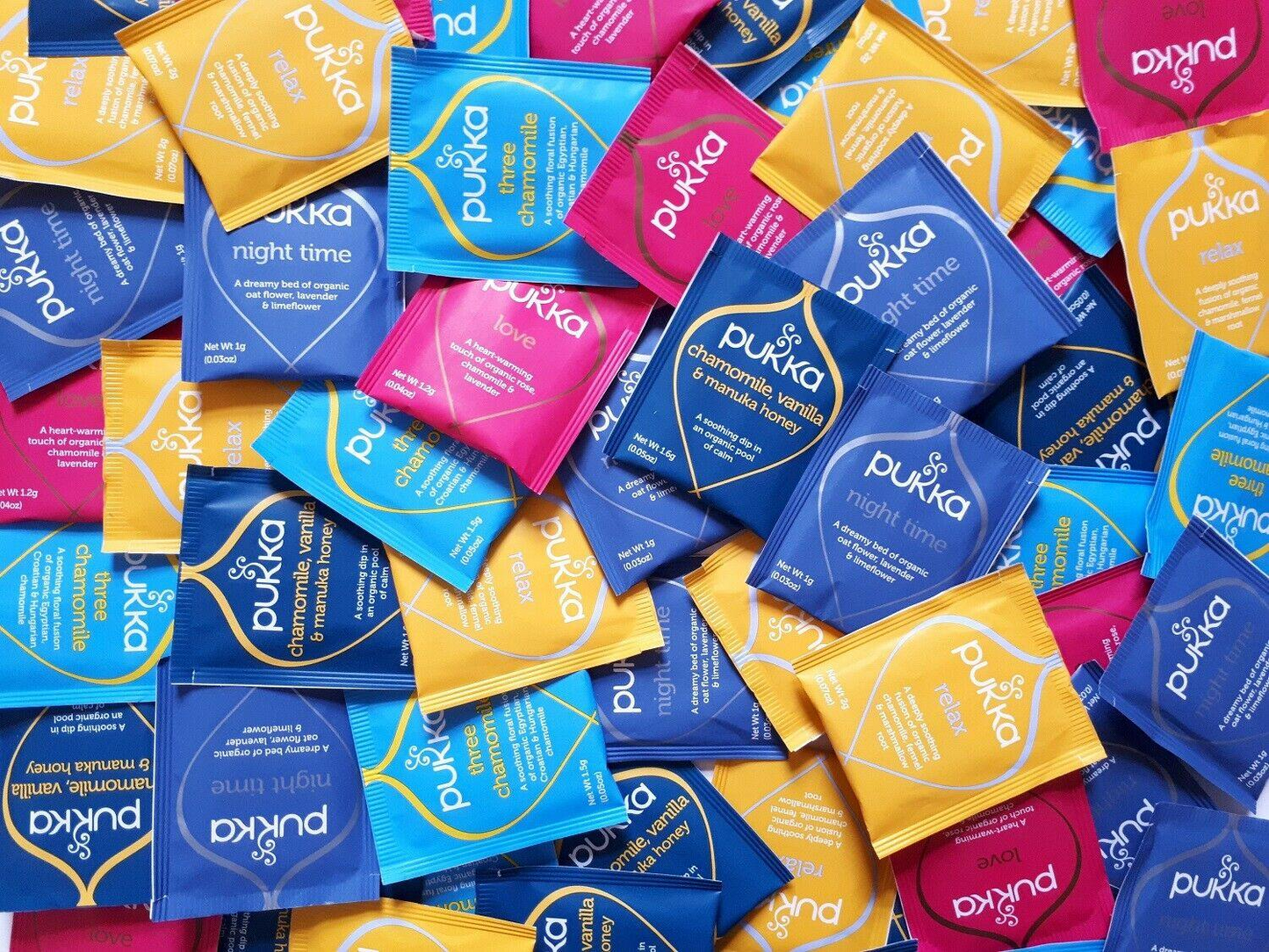 Assorted packets of Pukka herbal tea in various colors including blue, yellow, and pink.