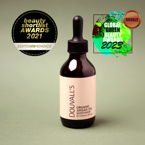 Bottle of Douvall's Organic Argan Oil Moisturizer with awards on a green background