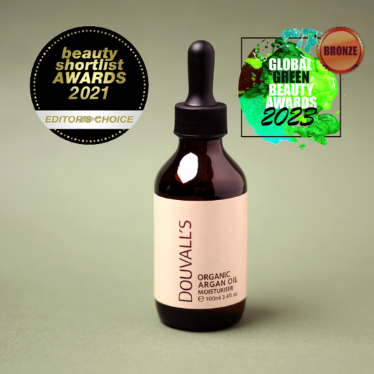 Bottle of Douvall's Organic Argan Oil Moisturizer with awards on a green background