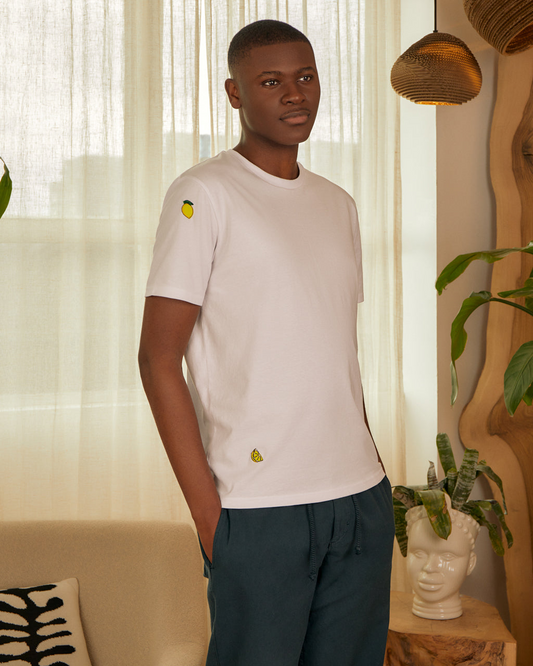 Man wearing a Lemon Embroidered Organic Cotton T-Shirt | Eco-Friendly & Stylish Crew Neck with small yellow embroidered lemons in a living room setting.