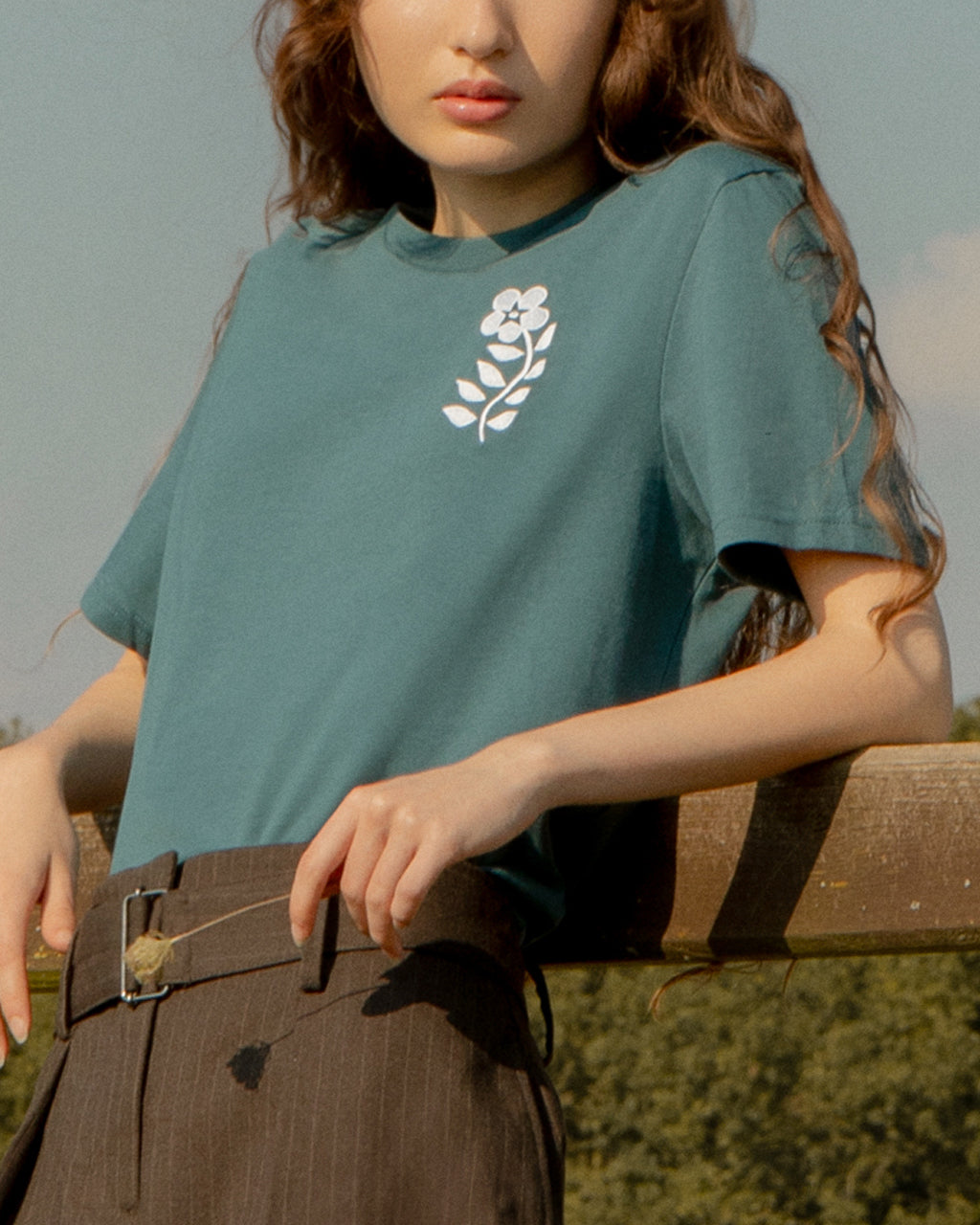 Person wearing a Eco-Friendly Floral Embroidered Organic Cotton Teal T-Shirt outdoors