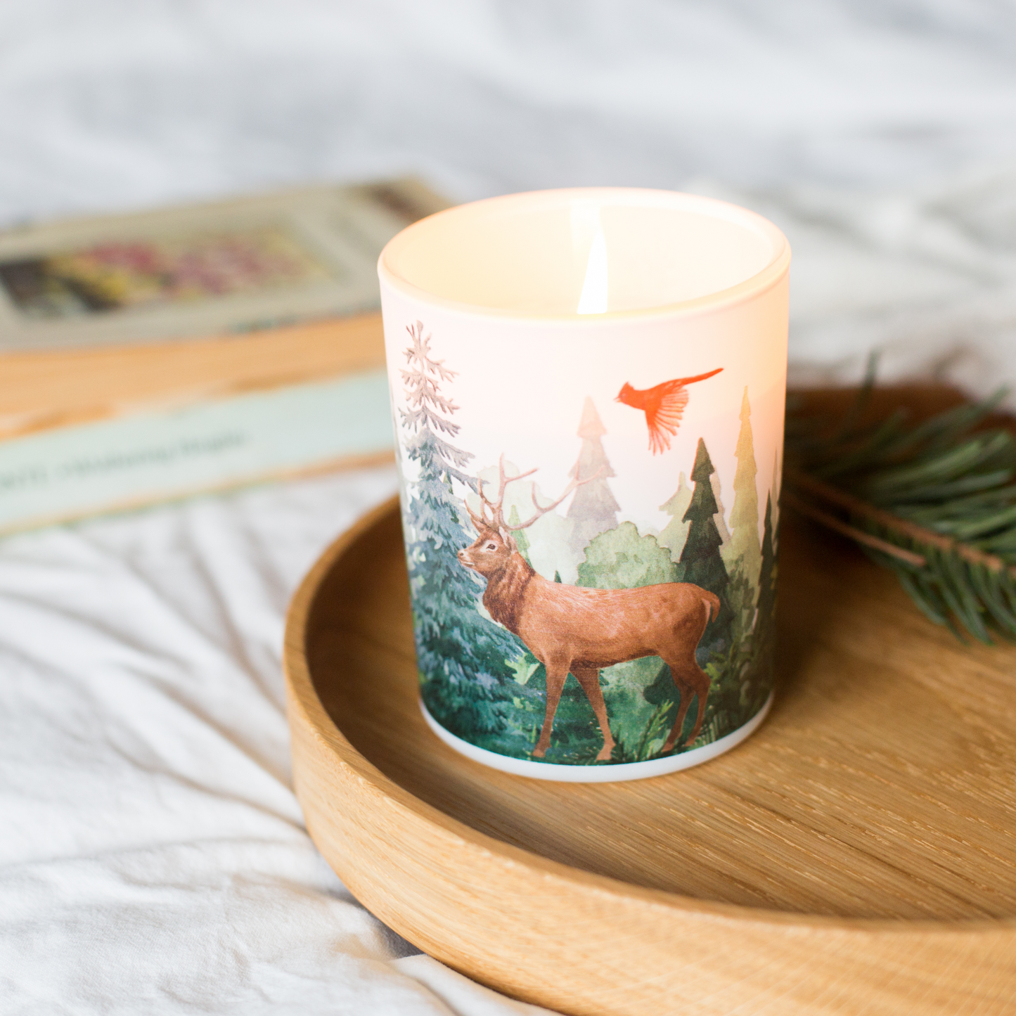 Candle with a deer design on a wooden surface