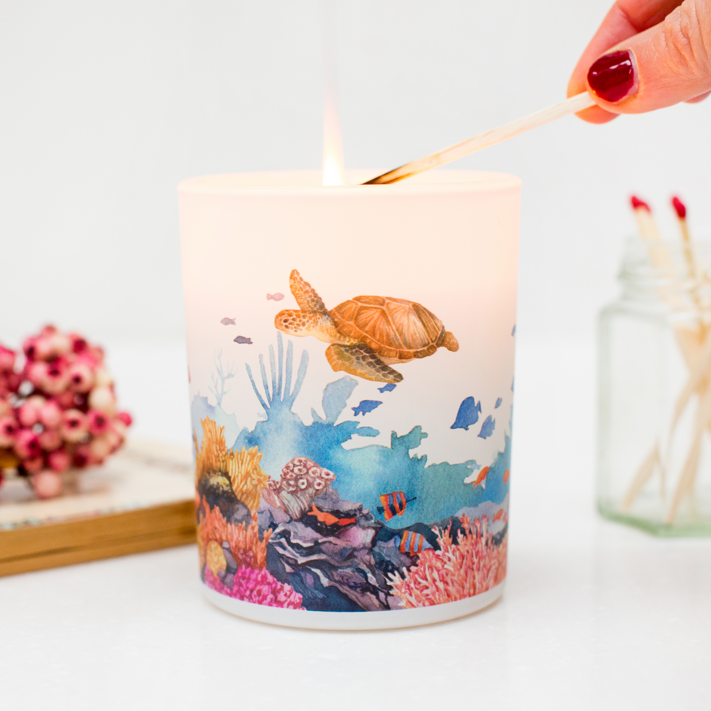 Candle with an underwater scene design being lit with a match.