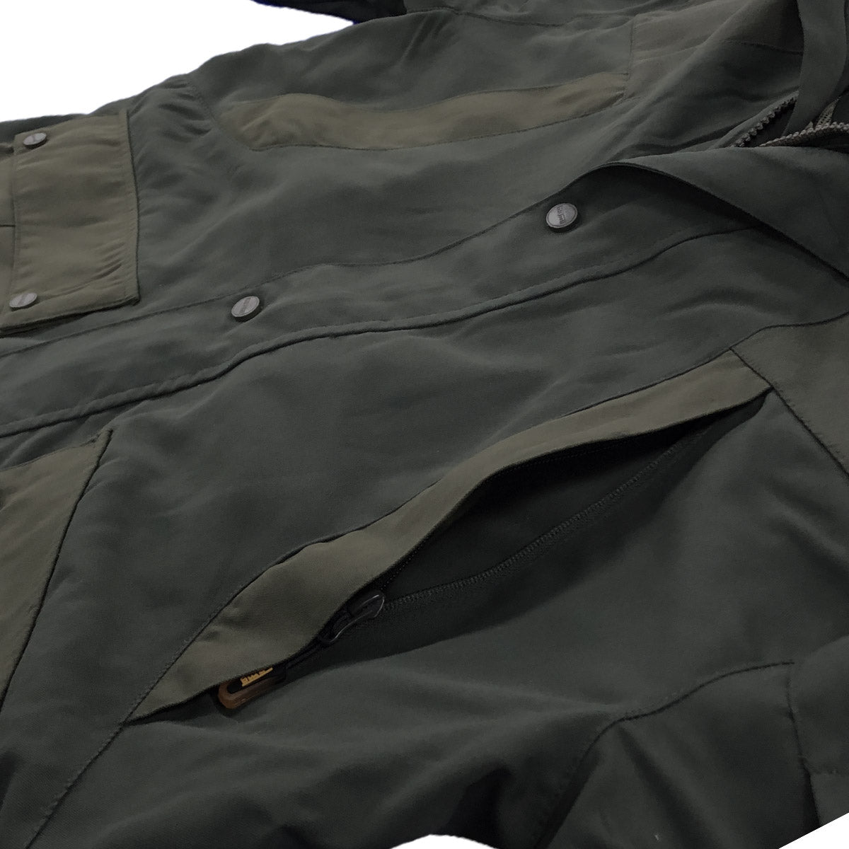Close-up of a dark green jacket with buttons and a brand logo.